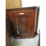 An early 18th century elm wall hanging corner cupboard, the moulded edges surrounding a single blind