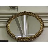 An ornate gilt framed oval mirror