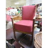 An early 20th century oak framed open armchair upholstered in a red fabric