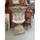 A reconstituted stone weathered urn on plinth, measures 104cm tall, planted with strawberries