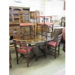 An early 20th century oak drop-leaf dining table along with a set of six (5 + 1) associated dining