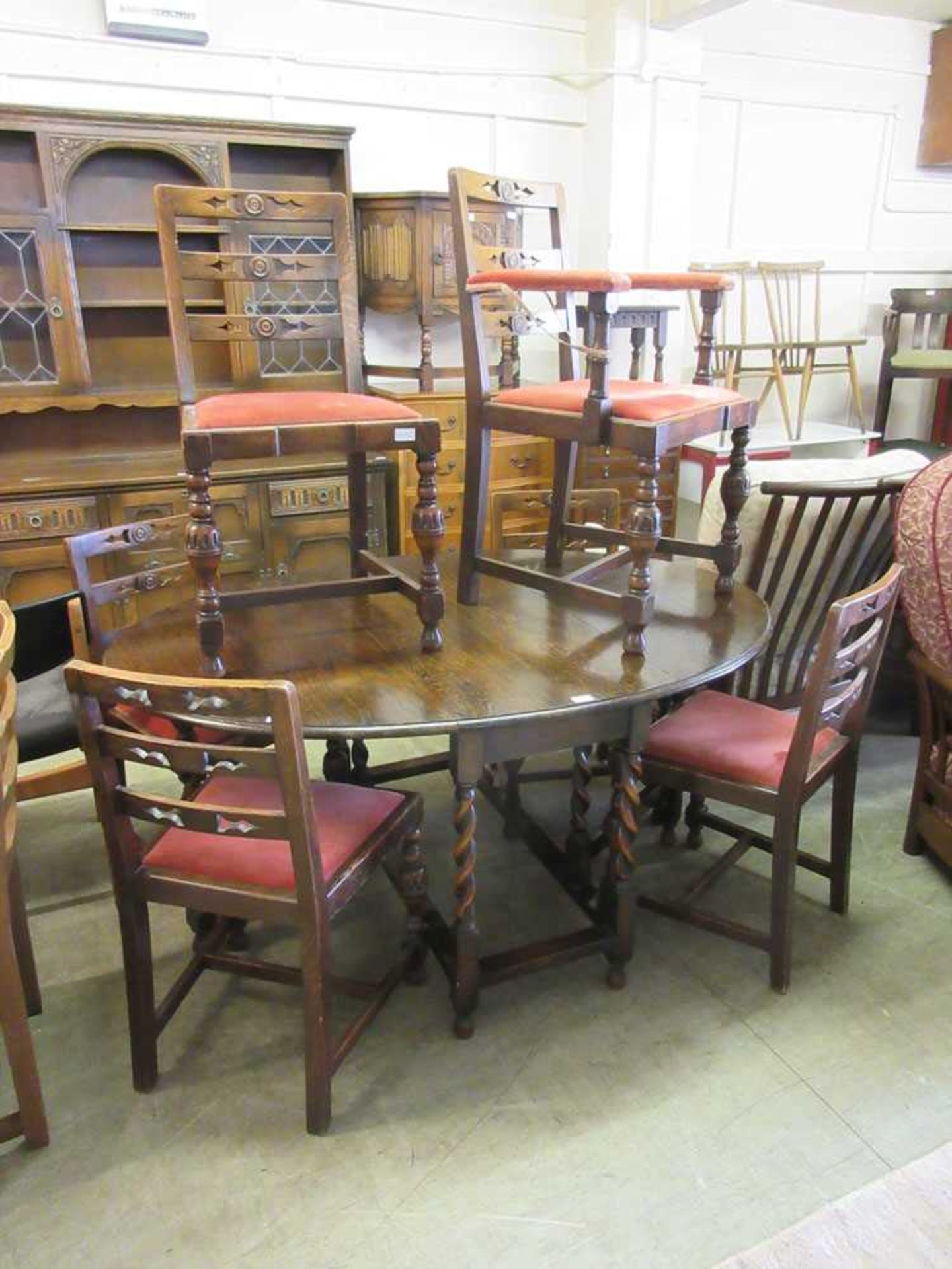 An early 20th century oak drop-leaf dining table along with a set of six (5 + 1) associated dining