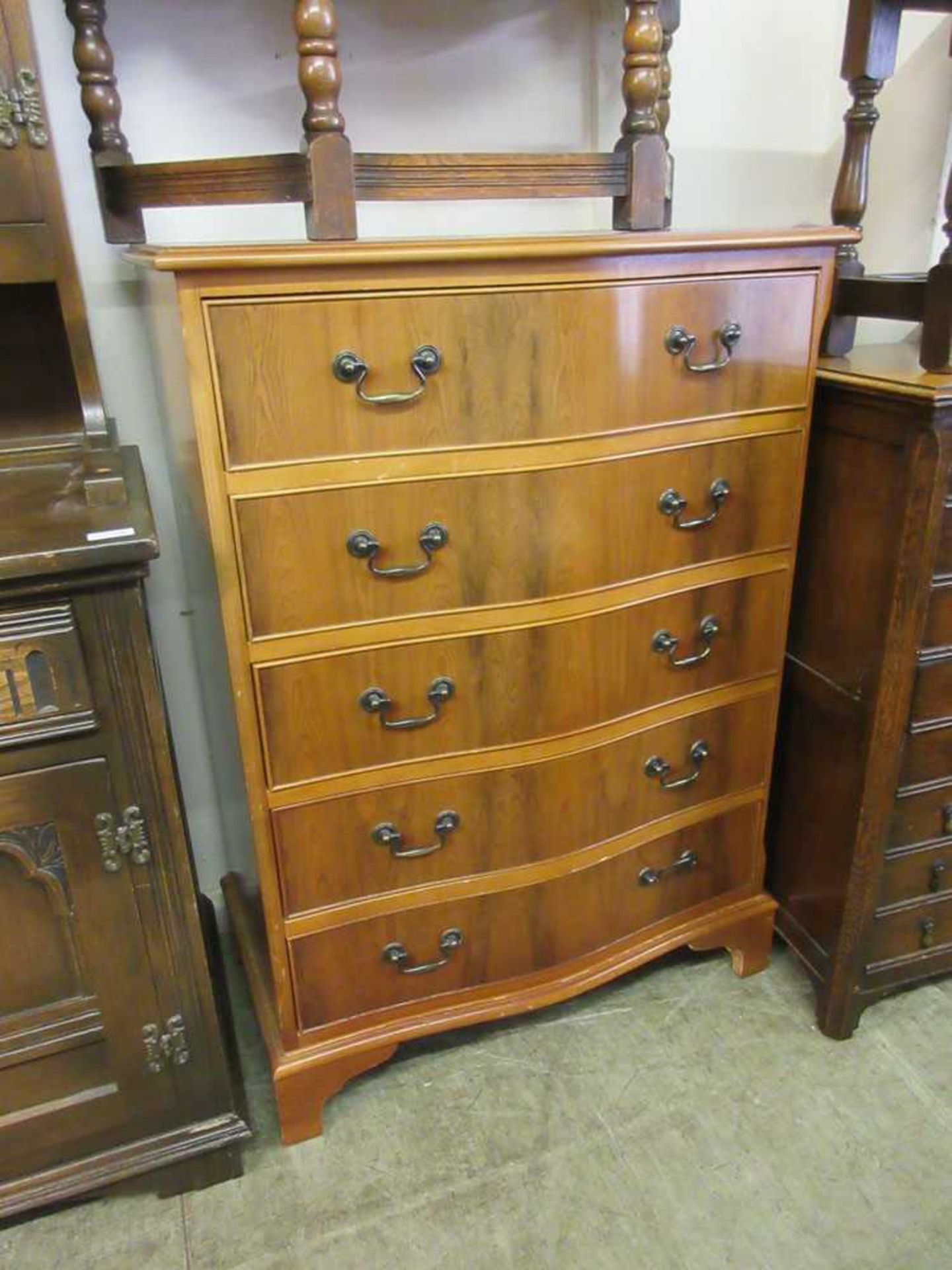A yew veneered serpentine chest of five drawers