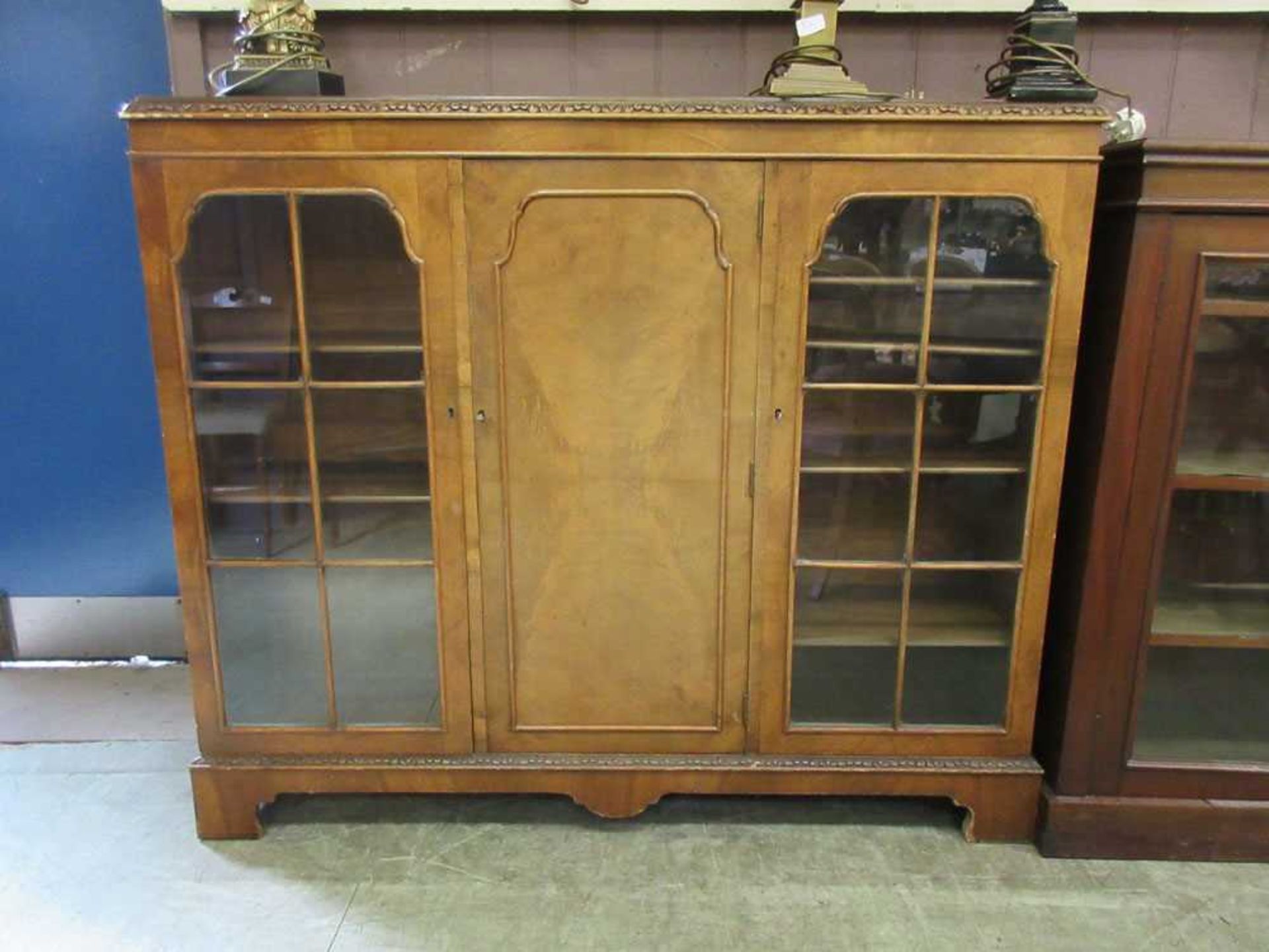 An early 20th century walnut side cabinet, the top over central cupboard door flanked by two