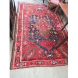 A handwoven Persian style red ground rug