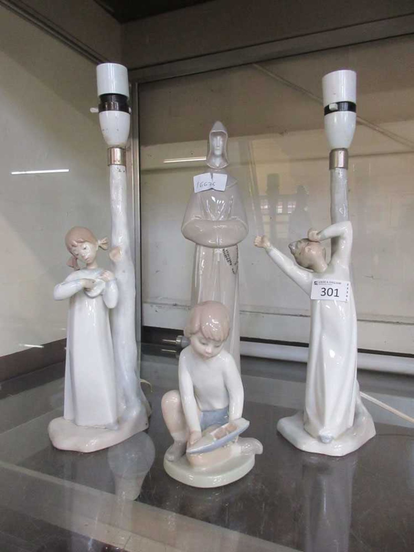A pair of Nao table lamps together with a Nao figurine of a monk and a Nao figure of young boy