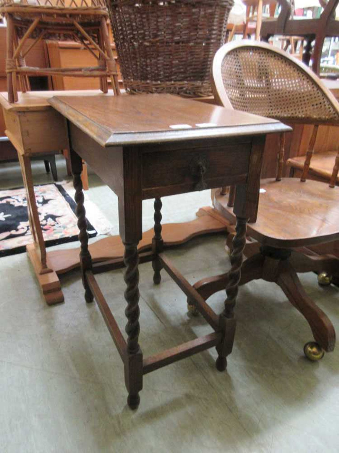 An early 20th century oak occasional table, the top over end drawer on barley twist legs