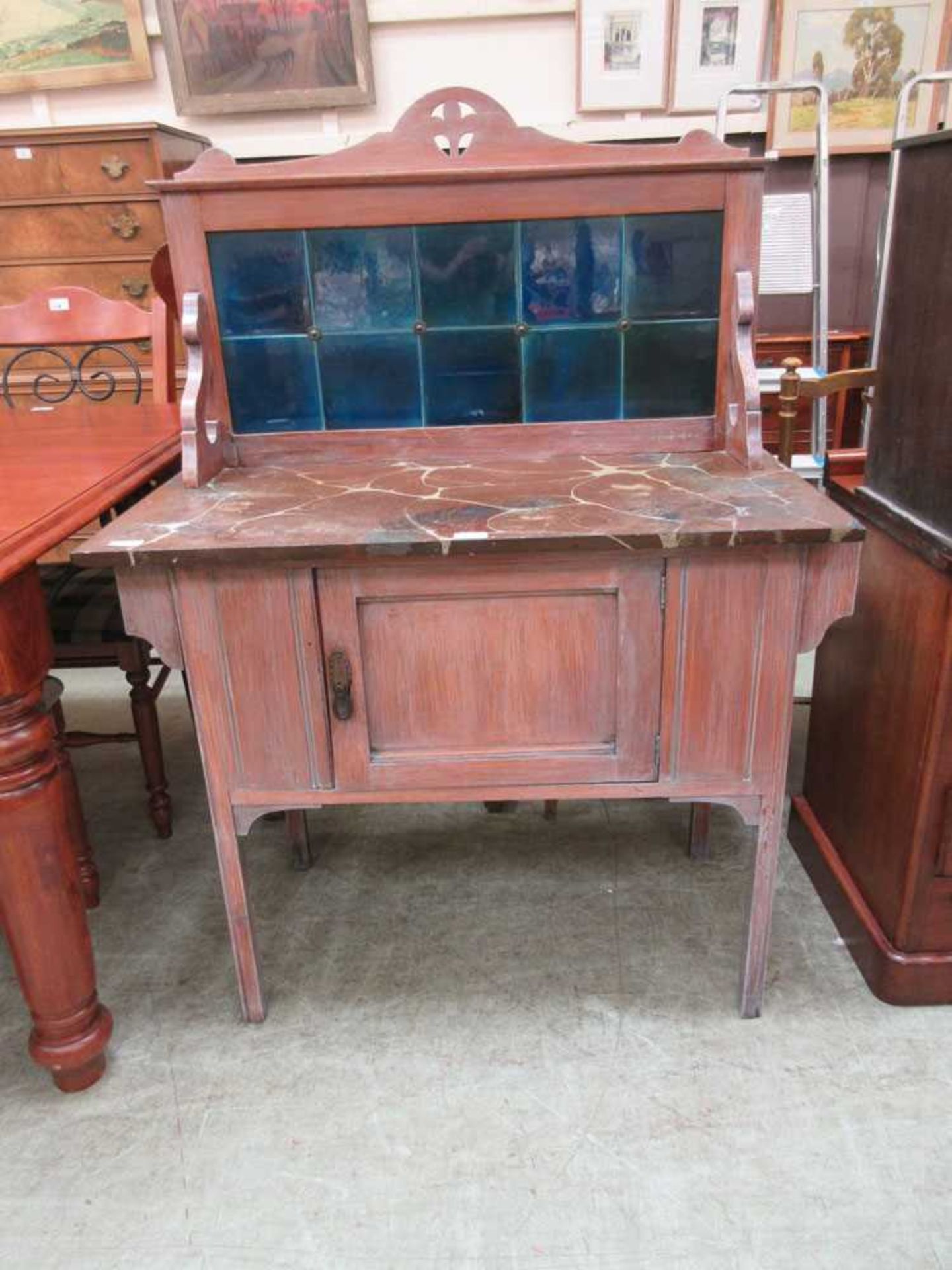 An early 20th century walnut washstand with blue tile back over marbled slate top