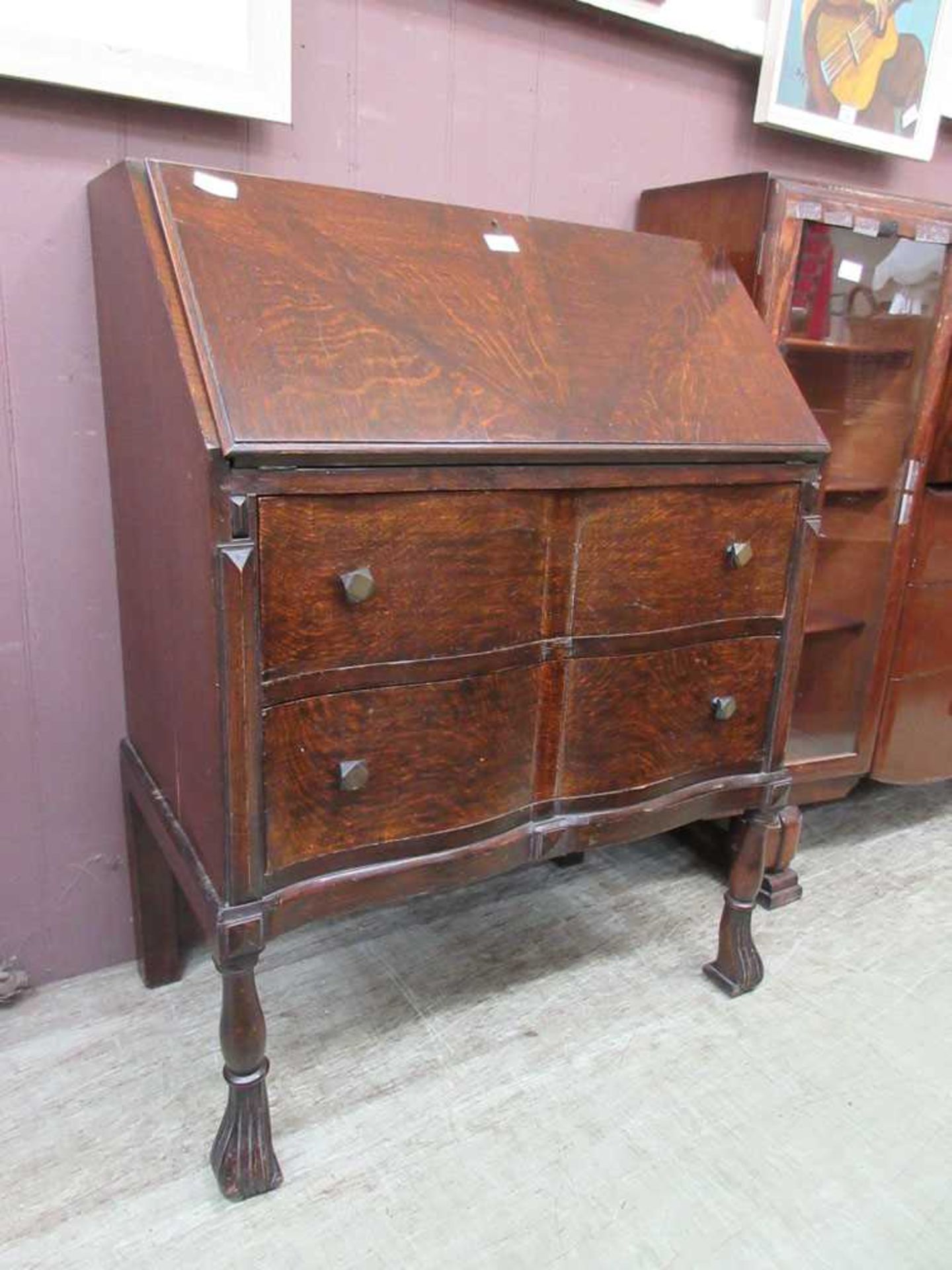 A 20th century oak veneered bureau, the fall front with fitted sliding interior over two shaped