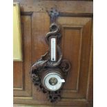 An early 20th century carved walnut thermometer/barometer with dragon design