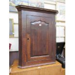 An 18th century oak wall hanging corner cupboard with arch topped field panelled door