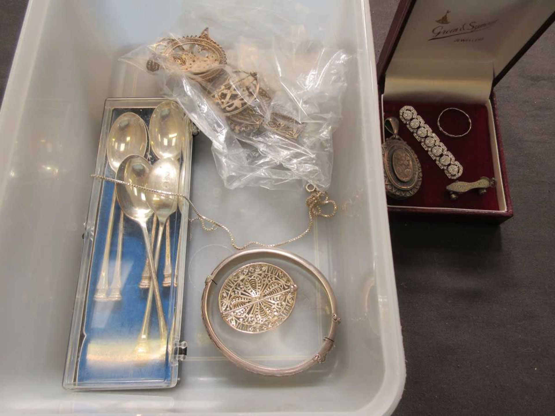 A box containing white metal and silver hallmarked items to include teaspoons, pendants, brooch,