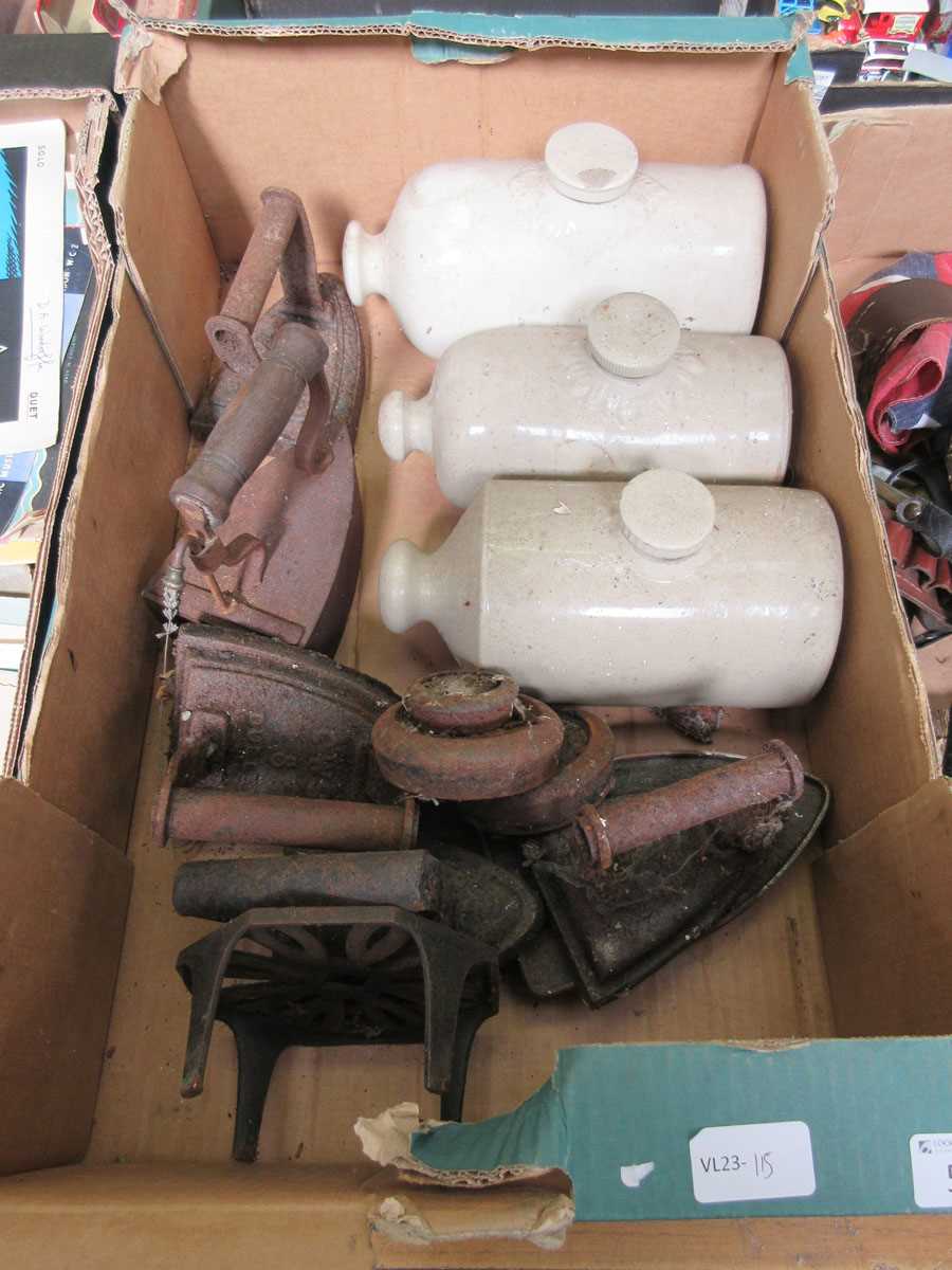 A tray containing irons along with three stoneware hot water bottles