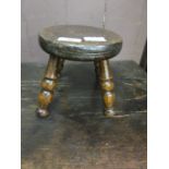 A 19th century ash milking stool on turned legs