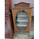 An Edwardian mahogany inlaid music cabinet with an oval glass fronted door