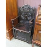 A late Victorian gothic style carved oak open armchair with pull down flap to under