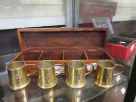 A wooden box containing four brass and copper toddy mugs