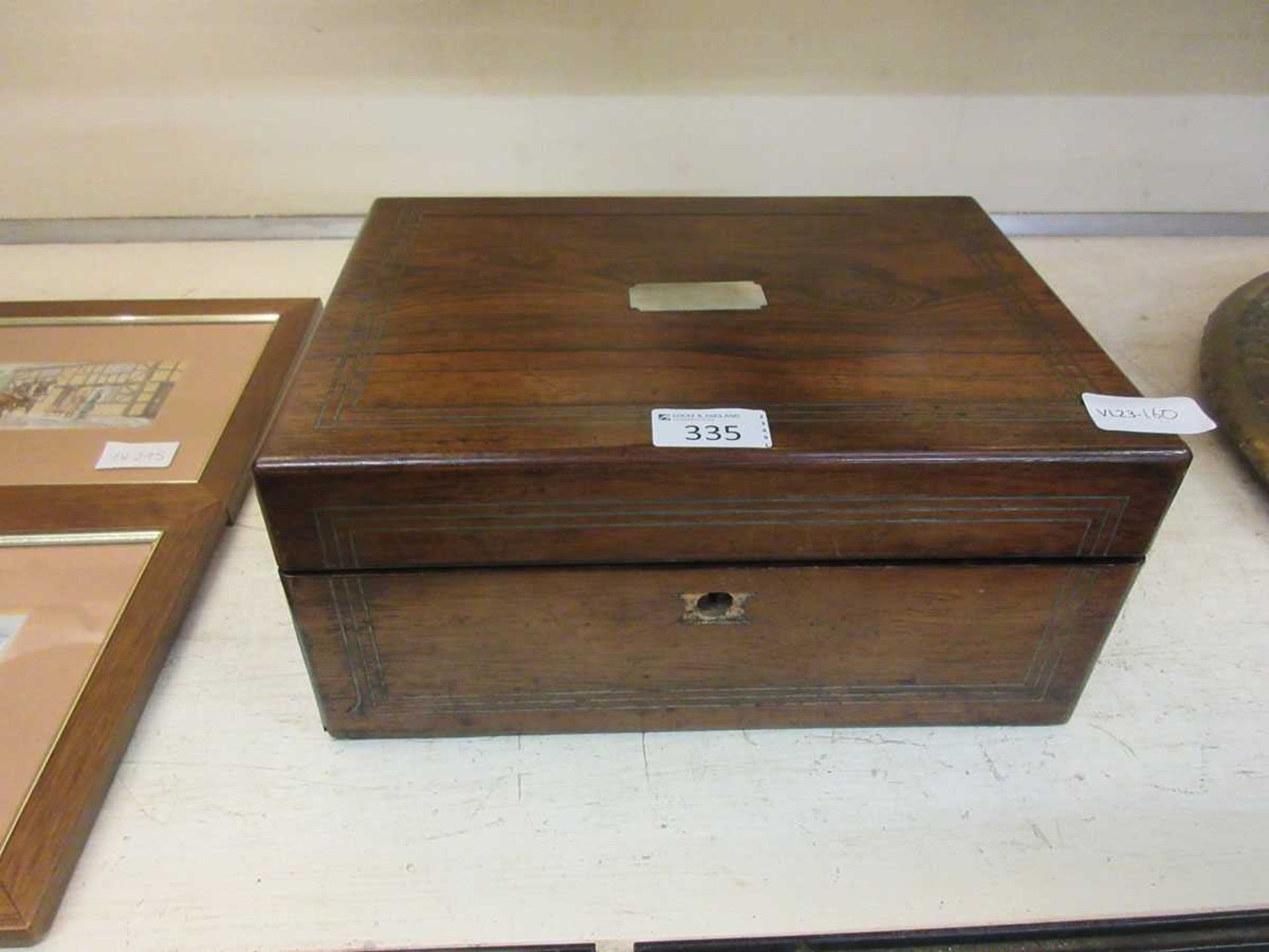 A wooden work box containing a selection of sewing and craft related items
