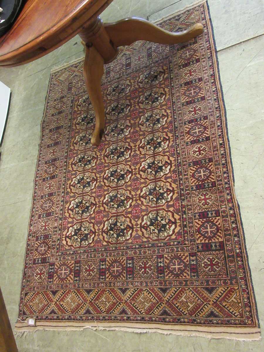 A rectangular Tekke Turkoman rug on a red and blue field measuring 120cm x 180cm