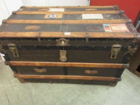 A vintage wooden and metal bound travelling trunk with some early labelling and interior fitments