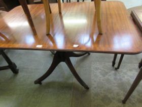 A reproduction inlaid mahogany extending dining table on quadruple supports