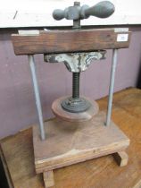 A hand operated metal and wooden framed press