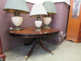 A reproduction mahogany oval coffee table on four splayed legs and paw feet