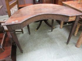 An oak writing table with shaped front and carved frieze