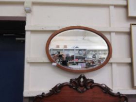 An Edwardian mahogany boxwood inlaid bevel glass oval mirror