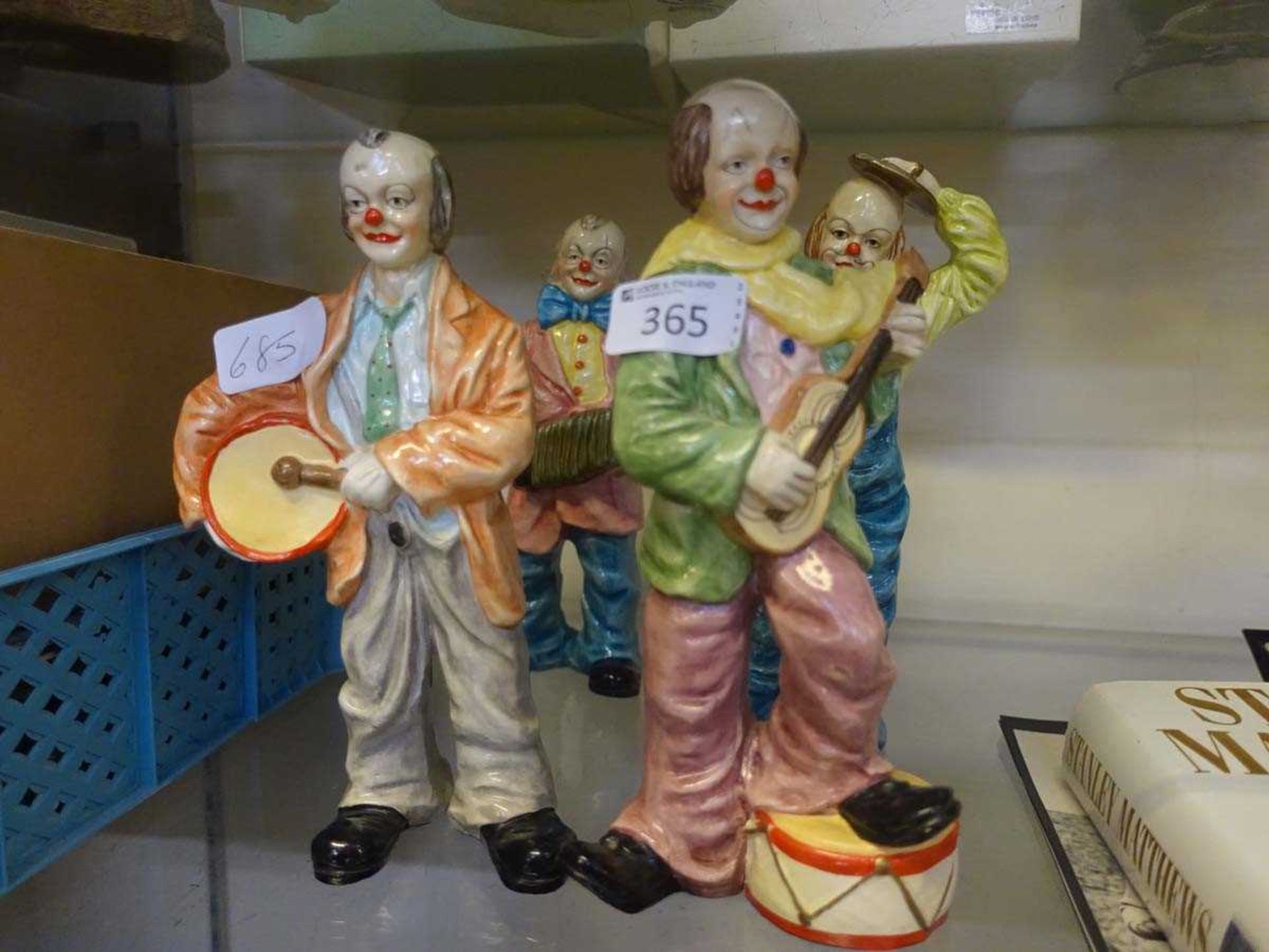 Four ceramic figurines of clowns playing musical instruments