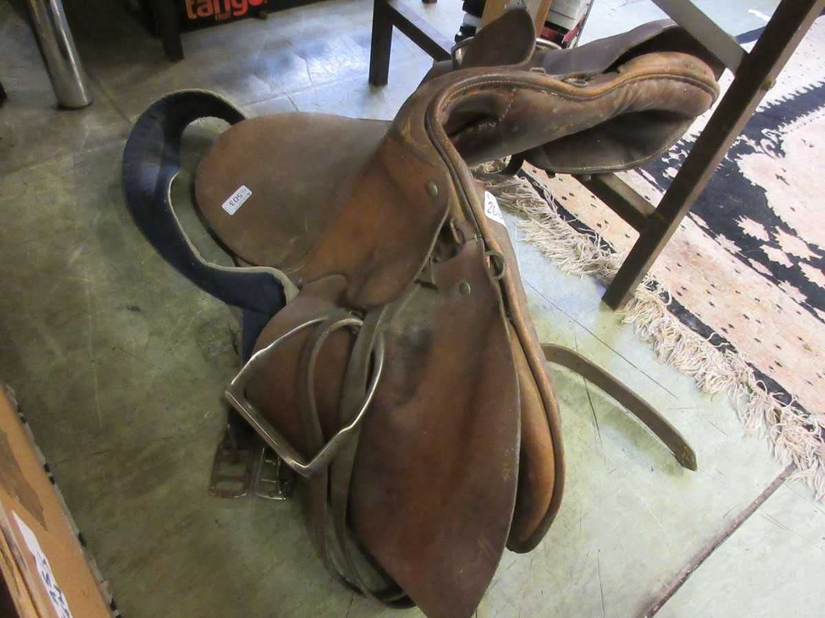 A brown leather saddle with stirrups