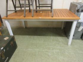A slated wooden topped table with cream metal legs