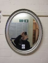 A silver painted oval bevel glass mirror