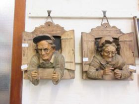 Two plaster moulded wall mounted plaques of elderly gentleman and elderly lady looking through