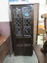 A dark oak full height corner cupboard having leaded glazed door to top with panelled door below