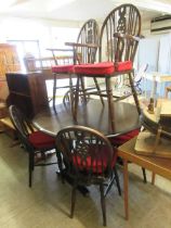 A dark oak drop leaf table together with a set of four standard and two carver matching wheel back