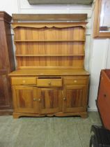 A modern pine dresser having plate rack to top, the base having three drawers above cupboard doors