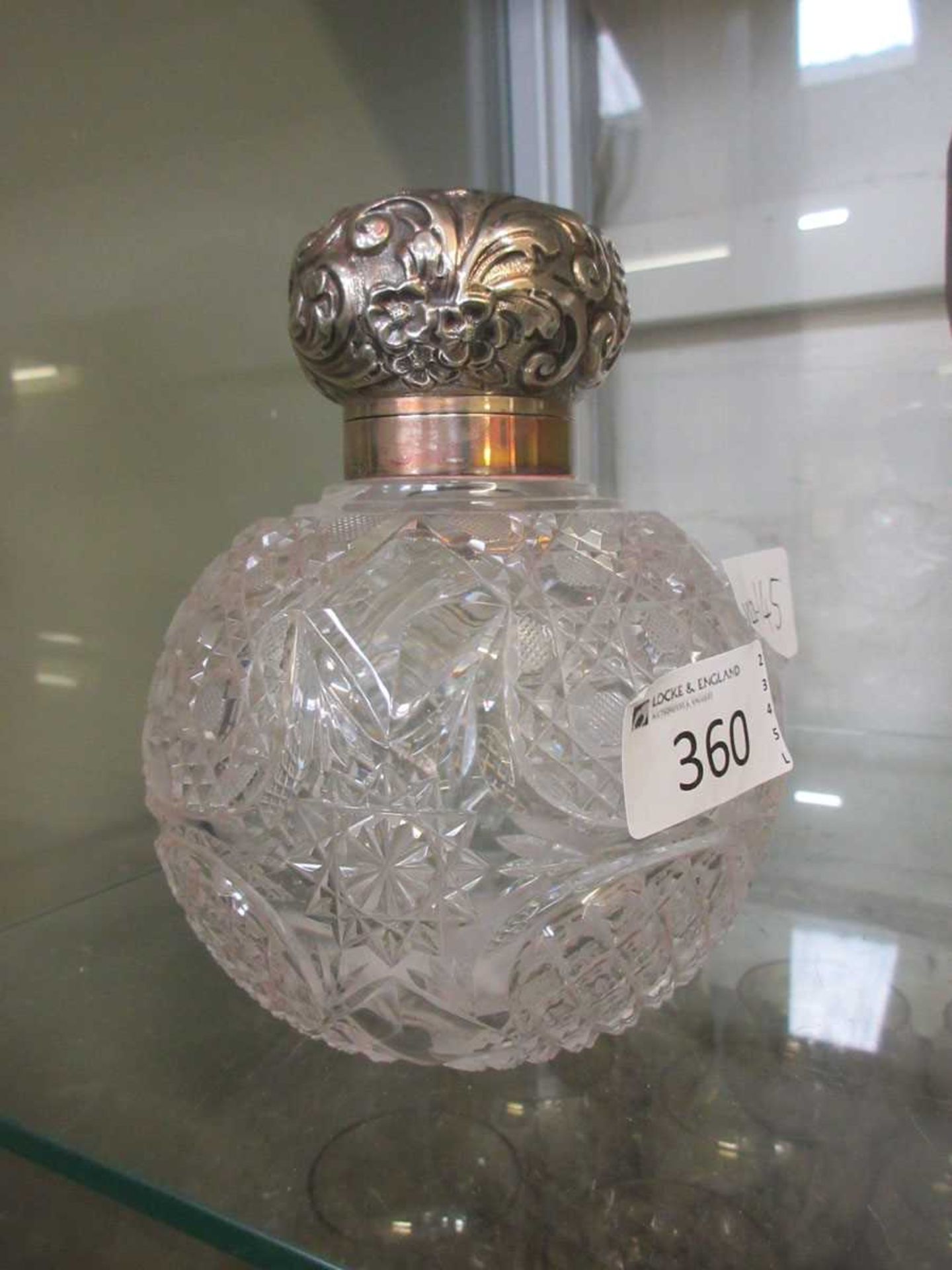 A spherical cut glass bottle with silver hallmarked lid