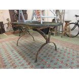 A metalwork table with a weathered stone top