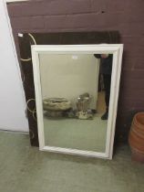 A white painted wall mirror together with a simulated suede covered framed wall mirror