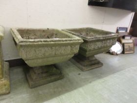 A pair of weathered concrete planters on bases
