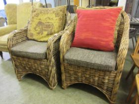 A pair of modern wicker chairs with brown upholstered cushions