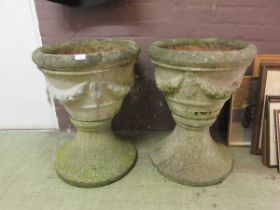 A pair of large weathered concrete garden urns on plinths