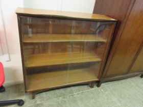 A teak bookcase with glass sliding doors