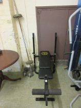 A Gold's Gym weight bench with two dumbell weights and a weight bar with weights