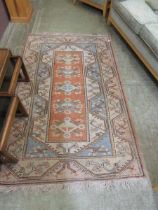 An orange ground eastern style rug with geometrical pattern to border and geometric medallions to