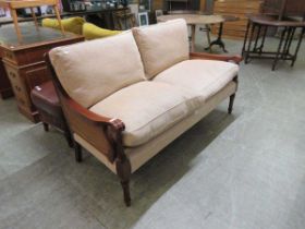 A reproduction regency style settee with cane back and sides