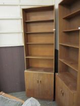 A mid-20th century teak full height bookshelf, the four shelves over a pair of cupboard doors