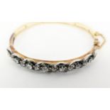 DIAMOND SET BANGLE, probably Edwardian, yellow metal, set with seven graduated diamonds, largest