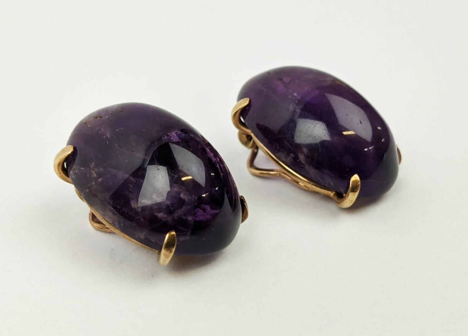 EARRINGS, a pair of amethyst cabouchon clip on earrings set in yellow metal, open backed, gross